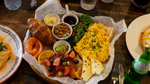 A platter of breakfast foods including eggs, fruit, coffee and a croissant.