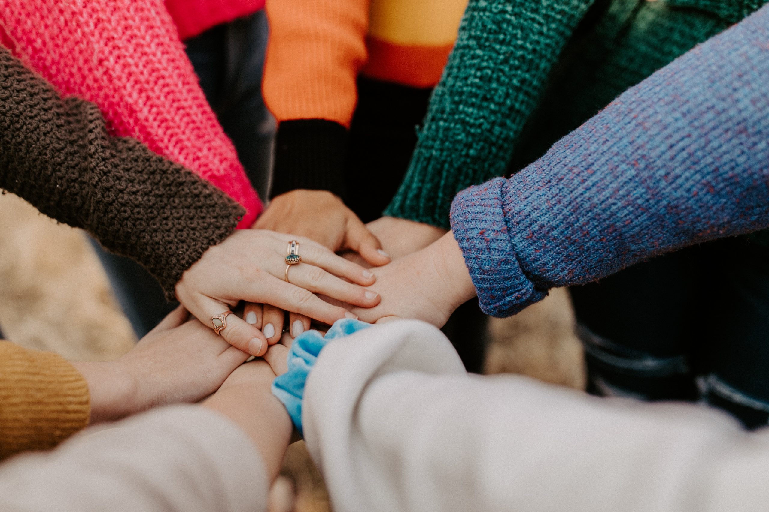 8 people stood in a circle touching their hands in the middle.