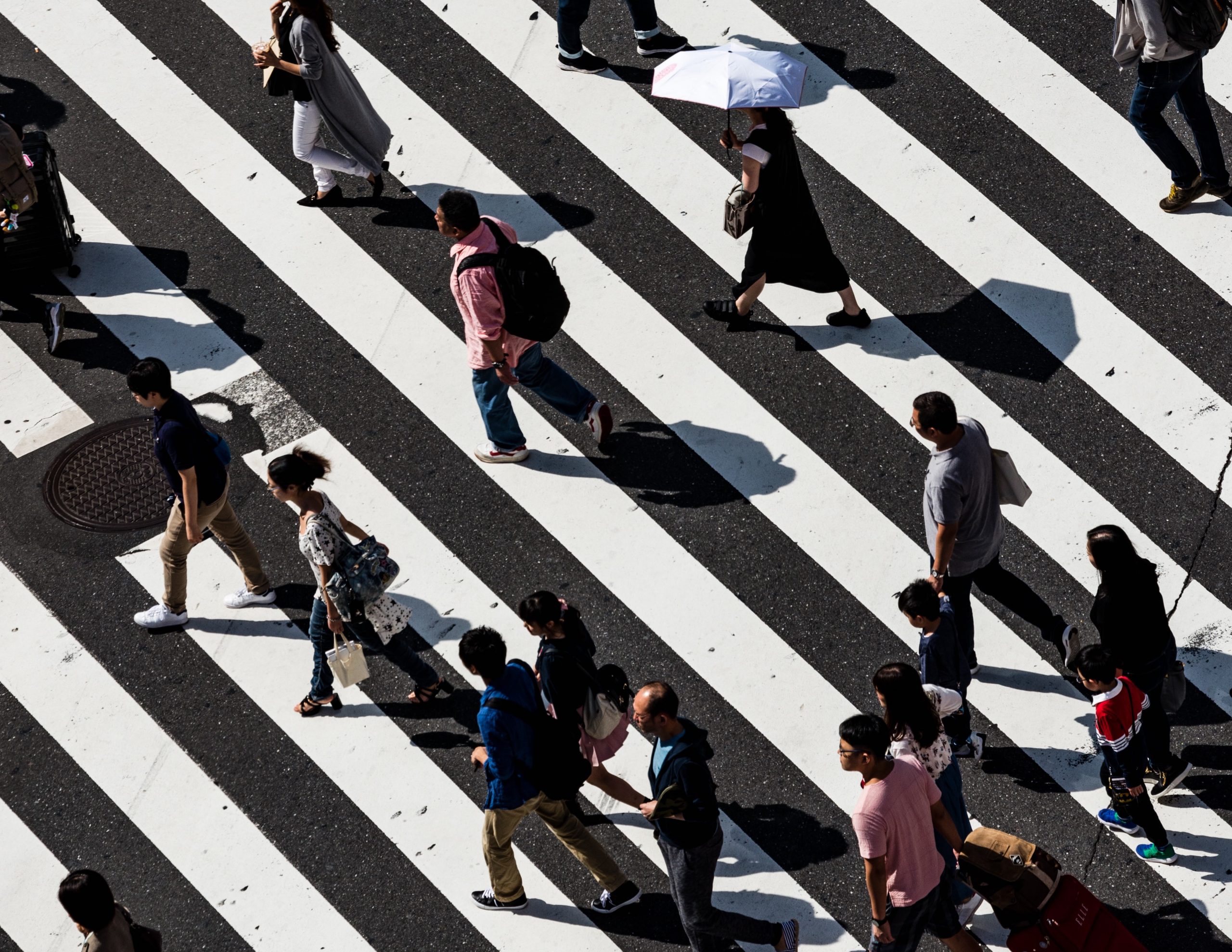 Diverse group of people walking across road