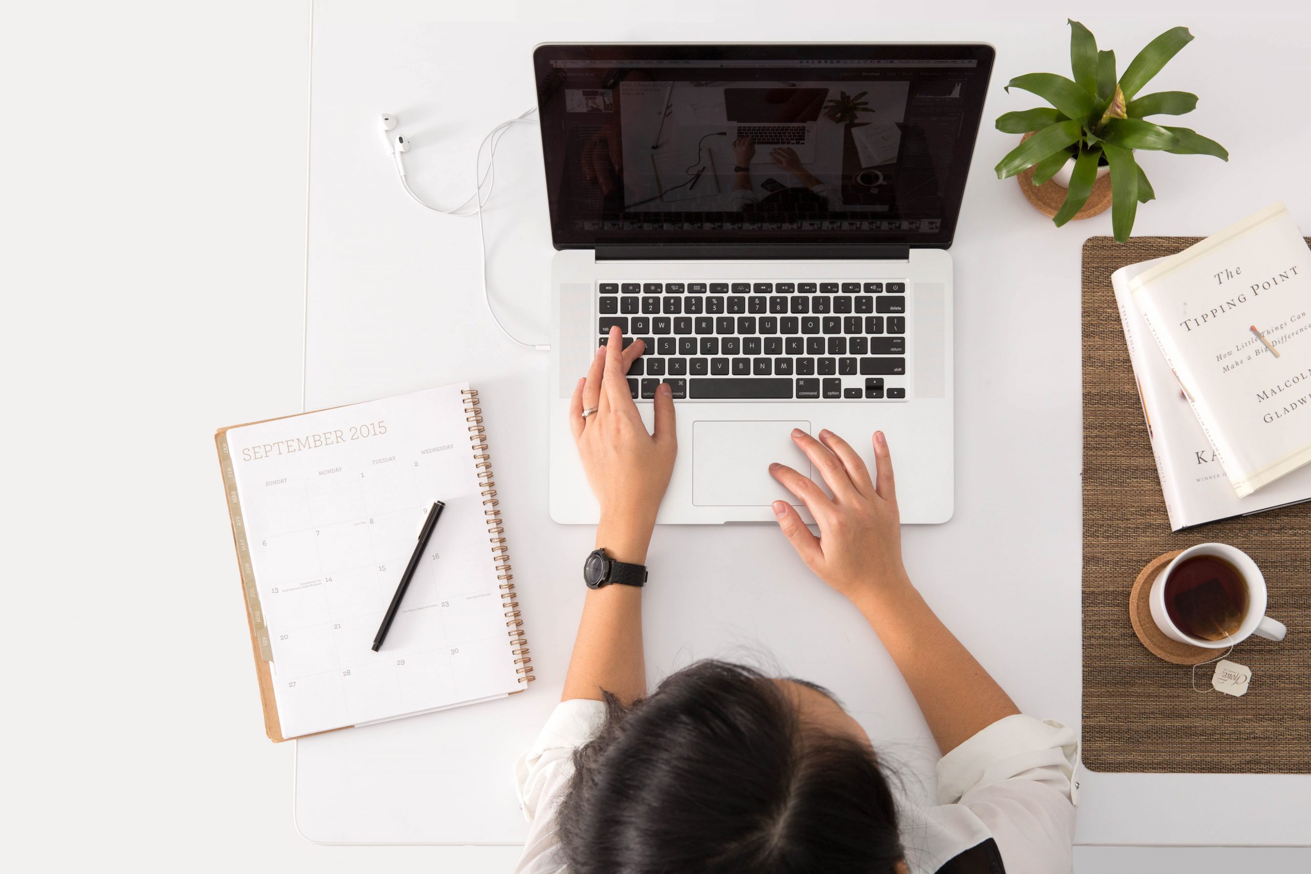 A candidate completing a work sample test on their laptop with a notebook and mug of coffee on their desk.