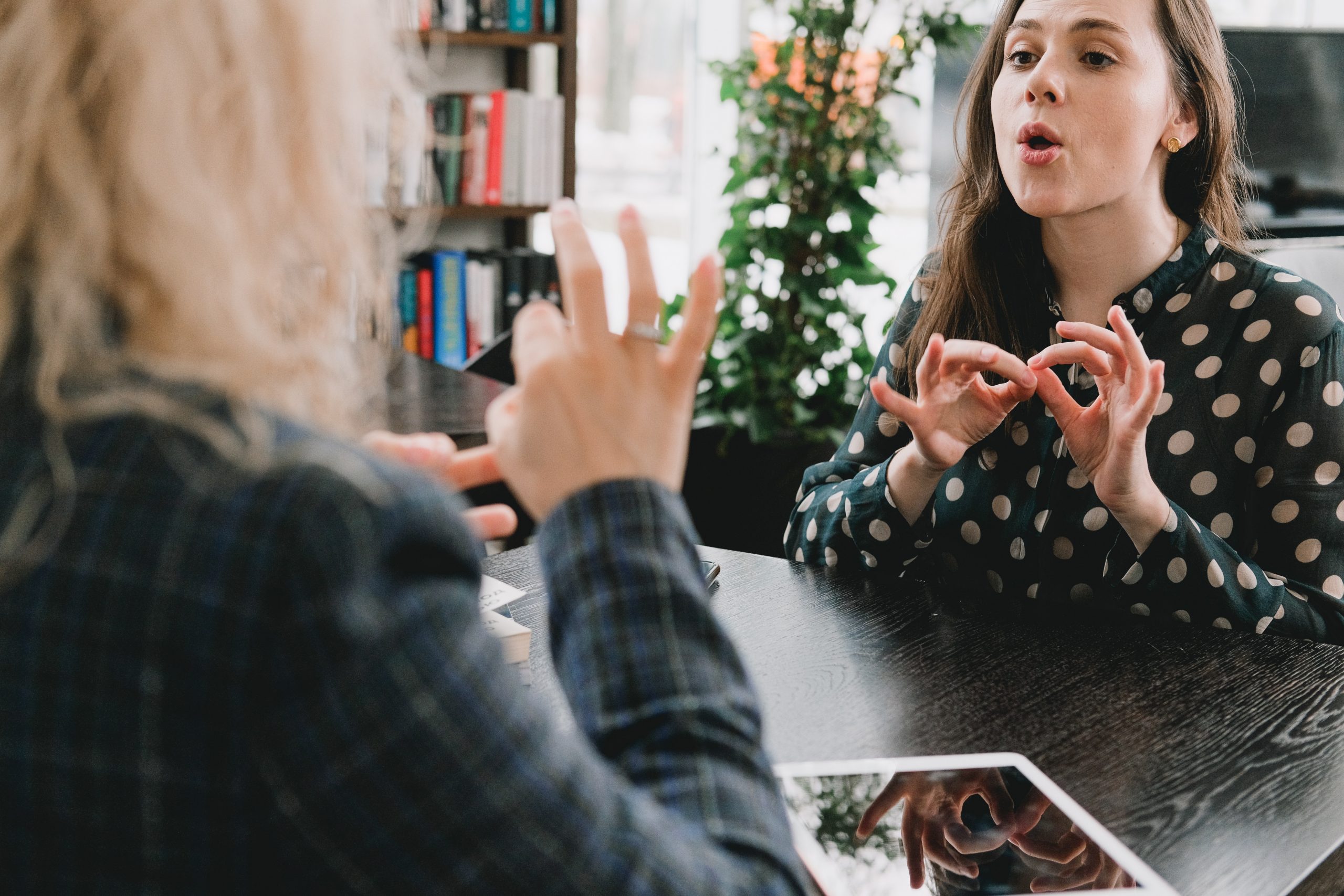 Two deaf women communicating with British Sign Language at work.